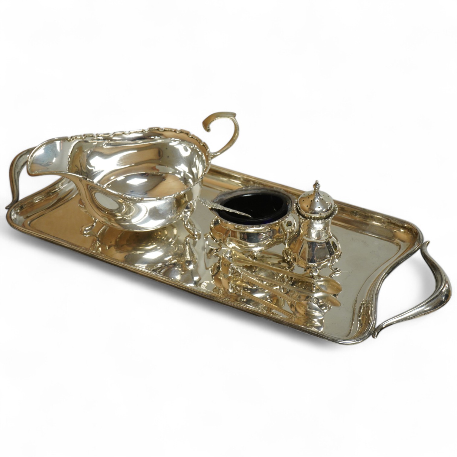 A George V silver sauceboat by Mappin & Webb, Birmingham, 1933, length 16.2cm, together with a silver salt and spoon, with blue glass liner, a silver pepperette, a pair of silver sugar tongs and a Spanish white metal two